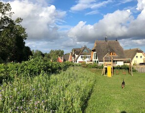 A rural landscape with traditional houses, a grassy field, and a wooden play structure.