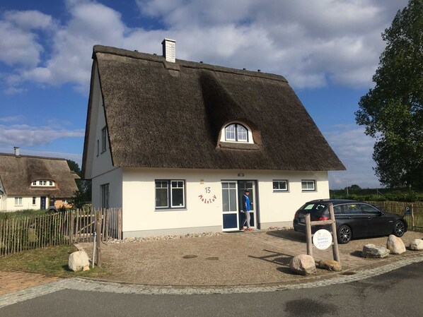 A thatched-roof house with a small porch, a door, and a window.