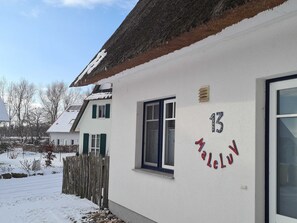 Un bâtiment blanc avec le chiffre « 13 » et le mot « Palau » inscrits sur le mur, une fenêtre et une porte.