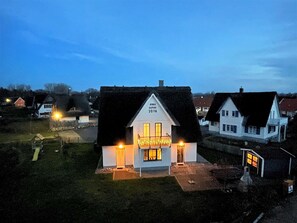 En hvid bygning med mørkt tag, et oplyst skilt og en lille veranda.