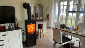 Una habitación acogedora con una estufa de leña, una mesa de comedor, sillas, un televisor y una ventana con vistas.
