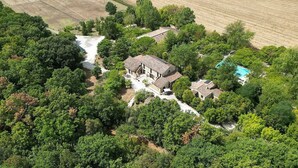 An aerial view of a property with multiple buildings surrounded by dense greenery, a visible swimming pool, and a small waterfall. - Villa Amarena B: A graceful apartment in the characteristic style of the Tuscan countryside, with Free WI-FI. (Massa Marittima)