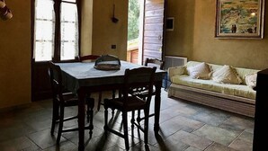 A dining area with a table and chairs, a sofa, and a painting on the wall. - Villa Amarena B: A graceful apartment in the characteristic style of the Tuscan countryside, with Free WI-FI. (Massa Marittima)