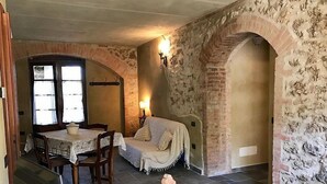 A dining area with a table and chairs, a sofa, and a brick wall with an archway.