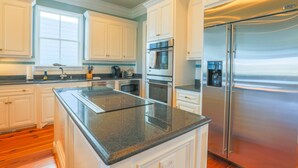 A modern kitchen with white cabinetry, stainless steel appliances, and a granite countertop.