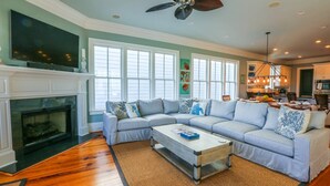 A spacious living room with a fireplace, a large sectional sofa, and a dining area with a chandelier.