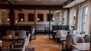 Un comedor moderno con suelo de madera, asientos acolchados e iluminación colgante.