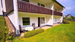 A two-story house with a balcony, a small patio with a table and chairs, and a well-maintained lawn. - Apartment-Wilmes - Burgstr. 15 Nr.2 (Winterberg)