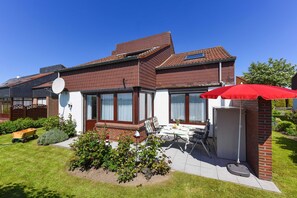 A two-story house with a patio, a satellite dish, and a small garden.