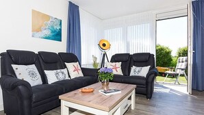 A living room with two black leather sofas, a wooden coffee table, and a floor lamp. - Ferienwohnung Schlipf in Carolinensiel - Ferienwohnung Schlipf (Wittmund)