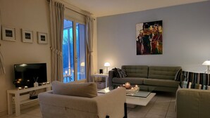 Ein Wohnzimmer mit einer Couch, einem Sessel, einem Fernseher und Kunstwerken an der Wand.