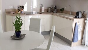 Eine moderne Küche mit weißen Schränken, einer Spüle, einem Herd und einem Essbereich mit Tisch und Stühlen.