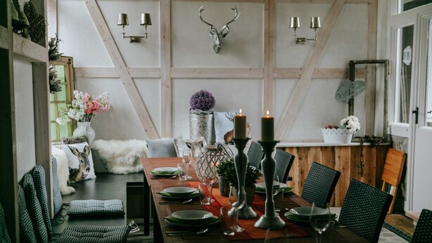 A dining area with a wooden table set for six, surrounded by green upholstered chairs. - Bergwald - Ferienwohnung Bergwald (Braunlage)