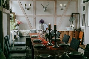 A dining area with a wooden table set for six, surrounded by green upholstered chairs.