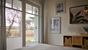 A bedroom with a large window, a bed, a bedside table, and wall decorations. - Arkona Beach, Deutschland (Breege)
