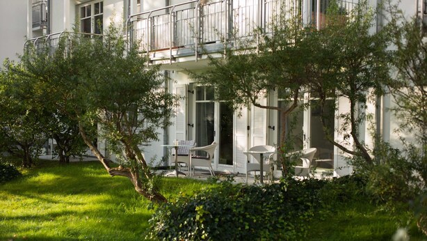 A building with a balcony, outdoor seating, and a well-maintained garden. - Arkona Beach, Deutschland (Breege)