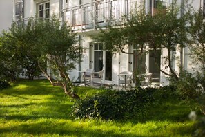 Een gebouw met een balkon, terras en een verzorgde tuin.