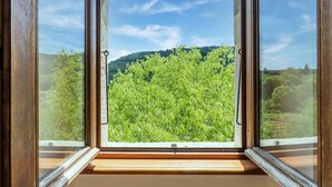 Une fenêtre donnant sur un paysage verdoyant et des collines.