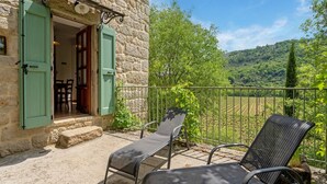 Un bâtiment en pierre doté d’un balcon, de deux fauteuils et offrant une vue sur un vignoble.