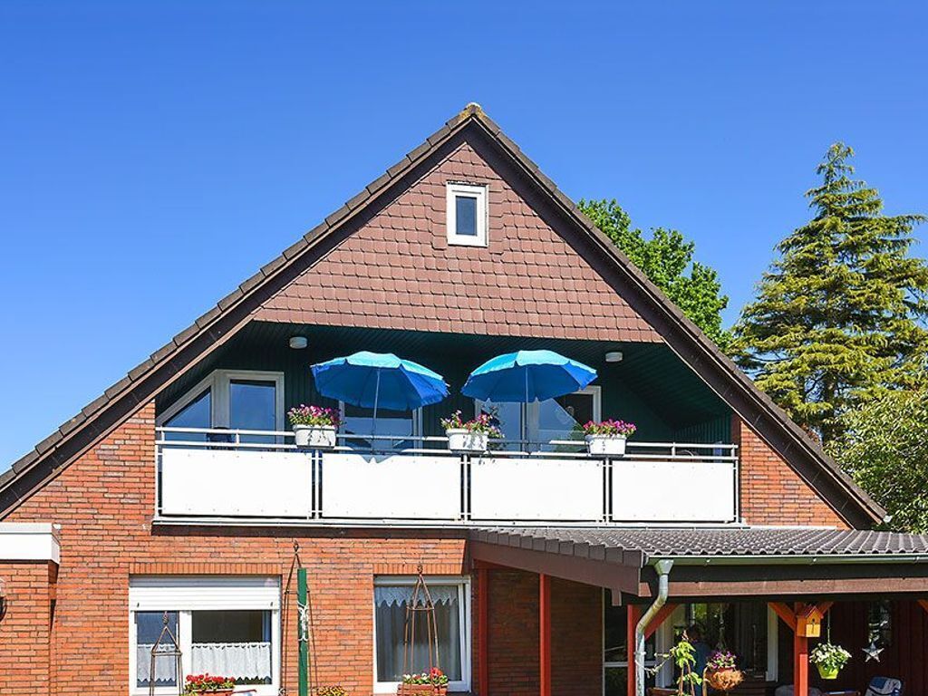 A two-story house with a balcony, a small window, and a covered porch area.