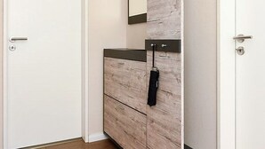 A room with a white door, a wooden panel wall, and a black towel hanging on a hook. - Ferienwohnung Haus Heimathafen (Esens)