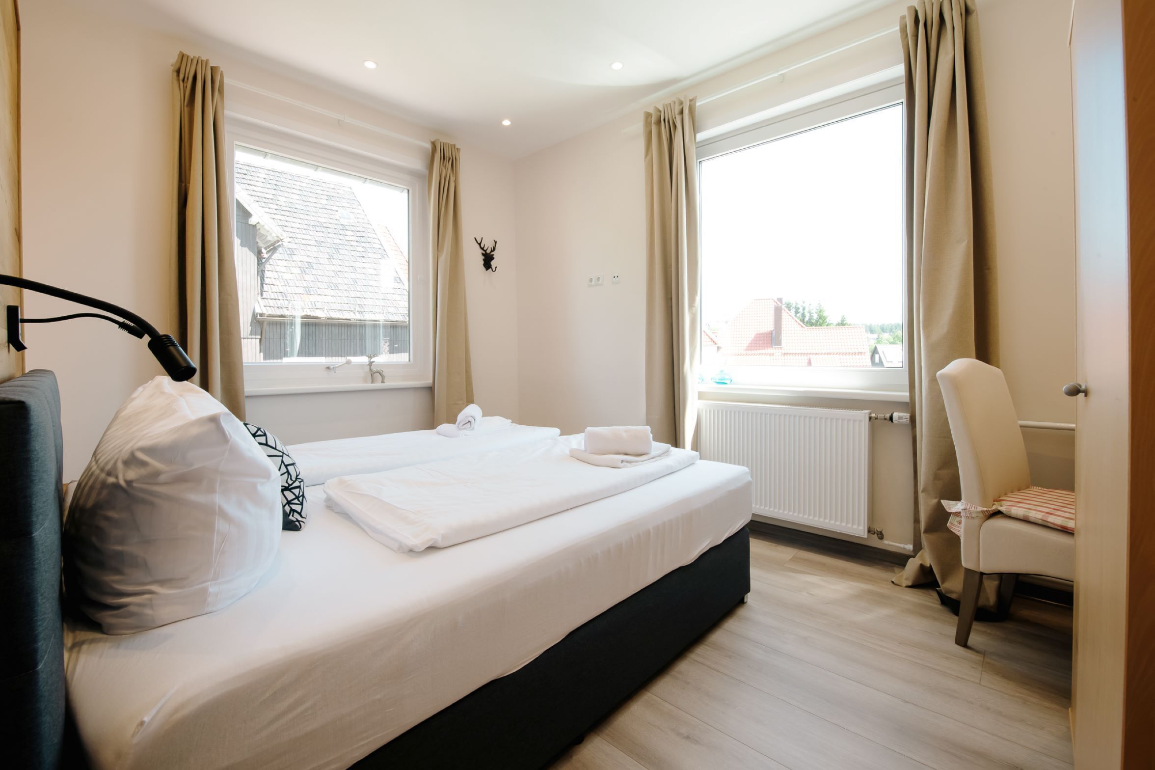 A hotel room with a bed, a chair, a window, and a radiator.