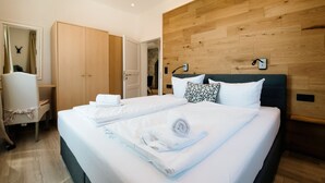 Ein modernes Hotelzimmer mit einem großen Bett, einem hölzernen Kopfteil und einem Schreibtisch mit Stuhl.
