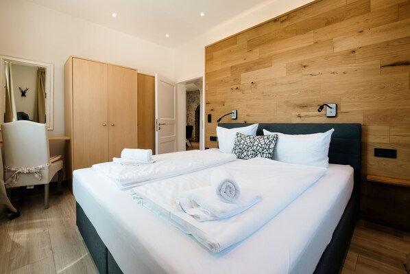A modern hotel room with a large bed, a wooden headboard, and a desk with a chair. - Morgensonne - Ferienwohnung Morgensonne (Braunlage)