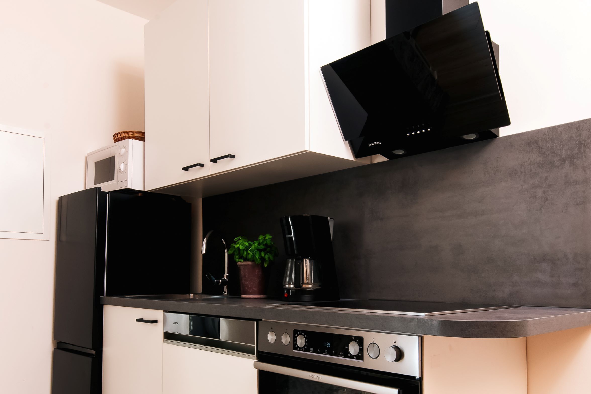 A modern kitchen with a built-in microwave, a coffee maker, and a stove.