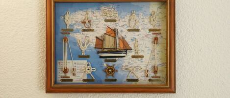 A framed nautical-themed artwork with a ship, anchors, and a compass.