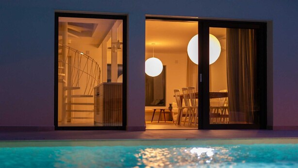 Una casa moderna con piscina, que cuenta con una escalera, comedor y ventanas amplias.