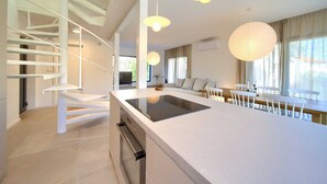 Una cocina moderna con una isla central, armarios blancos y una escalera espiral.