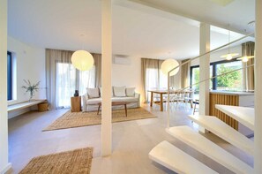 Relax in a spacious living area with a sofa, coffee table, and staircase leading to an upper level.