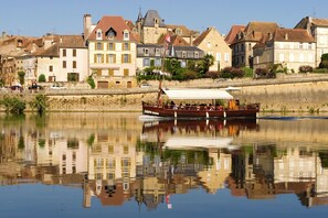 A boat with passengers on a calm river, reflecting buildings in the background. - Modern holiday home with swimming pool (St Nexans)
