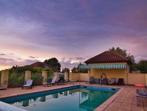 A pool area with lounge chairs and a covered seating area.