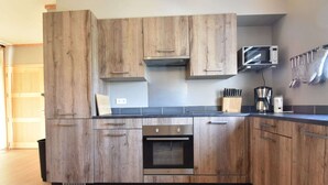Una cucina moderna con mobili in legno, un forno a microonde, una macchina da caffè e un portacoltelli.
