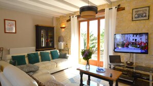 A living room with a sofa, a coffee table, a TV, and a stone wall. - Family Retreat in Thédirac (Thedirac)
