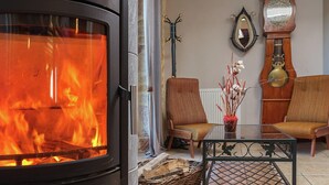 A cozy living room with a wood-burning stove, two chairs, a table, and a decorative mirror. - Family Retreat in Thédirac (Thedirac)