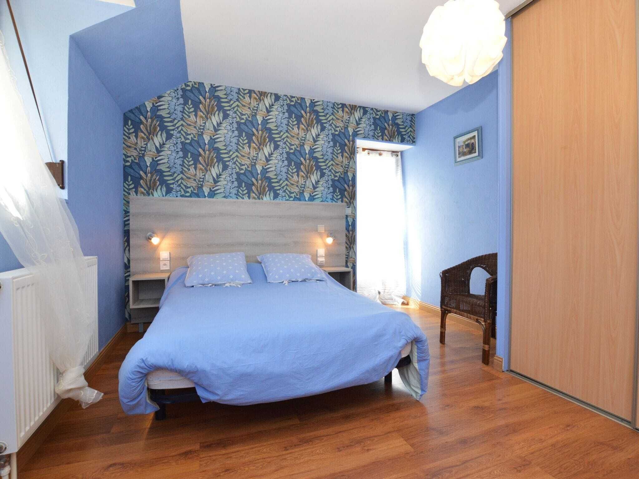 A bedroom with a bed, a nightstand, a dresser, and a window with curtains.