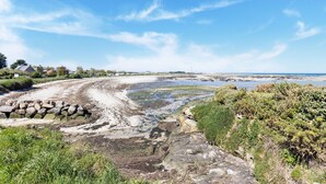 A coastal landscape with a sandy beach, rocky outcrops, and lush greenery. - Charming Home with Orchard (Montaigu-La-Brisette)
