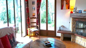 A cozy living room with a sofa, a wooden table, and a fireplace. - Villa in Le Boulou with Scenic Hilltop Views (Le Boulou)