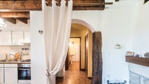 A kitchen with wooden flooring, a hanging curtain, and a fireplace.