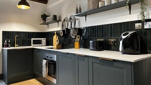 Une cuisine moderne avec des meubles de couleur sombre, un plan de travail blanc et un revêtement mural noir.