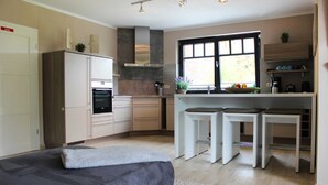 Cozinha moderna com ilha central, eletrodomésticos embutidos e uma ampla janela que proporciona iluminação natural.