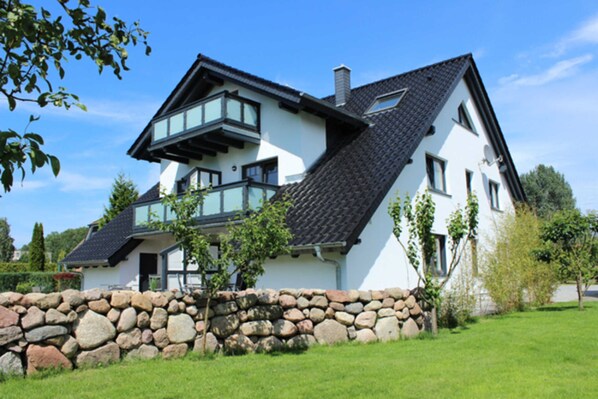 A modern house with a stone foundation, large windows, and a sloped roof.