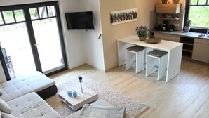 A modern living room with a sofa, coffee table, and a dining area with a small table and chairs. - Ferienwohnung 6 - Ferienhaus Luise Urlaubslust Trassenheide (Trassenheide)