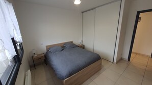 A bedroom with a bed, bedside tables, a wardrobe, and a window with curtains.