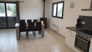 A modern kitchen with a stove, oven, and dining area with chairs and a table.