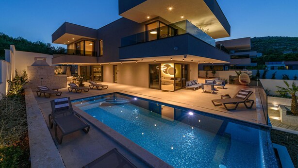 A modern two-story house with a swimming pool, outdoor seating, and a well-lit patio area. - Cozy home in Marina with sauna (Marina)