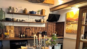 Una sala de estar acogedora con un sofá de cuero marrón, una mesa de centro de madera y un cuadro de un atardecer.